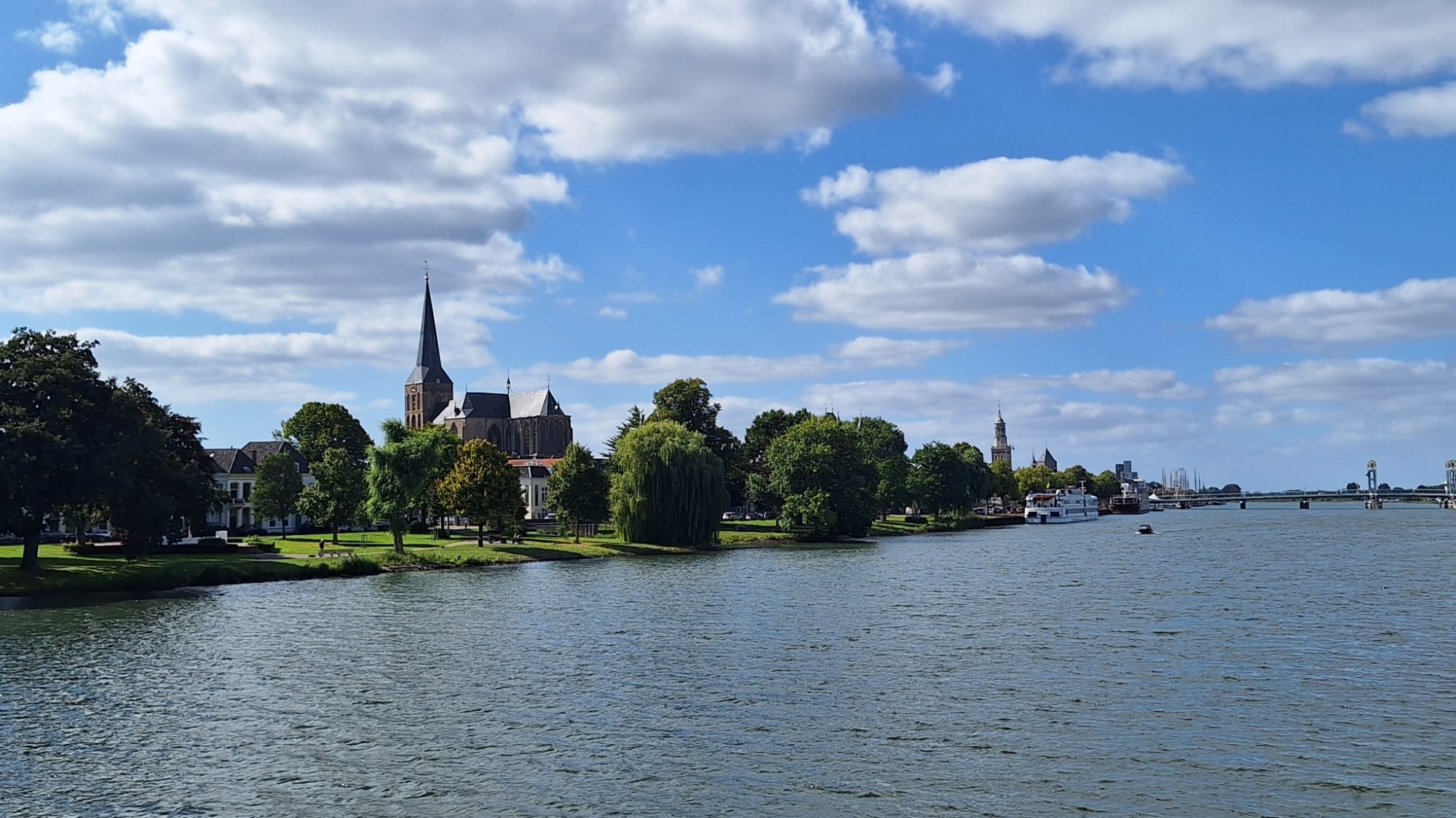 Uitzicht over de brede IJssel naar IJsselmuiden met kerktoren en groene oevers